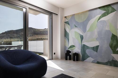a living room with a chair and a large window at Dea Luna Villas, Heated Pool & 5star Resort Access, By ThinkVilla in Panormos Rethymno