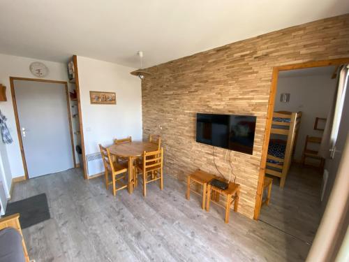 - un salon avec une table et des chaises ainsi qu'un mur en briques dans l'établissement Superbe appartement au cœur de la joue du loup, à Saint-Étienne-en-Dévoluy