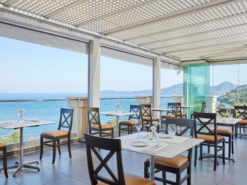 a restaurant with tables and chairs and a view of the ocean at MarBella, Mar-Bella Collection in Agios Ioannis Peristeron