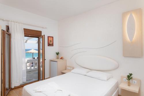 a bedroom with a bed and a view of the ocean at Kokkari Beach Hotel in Kokkari