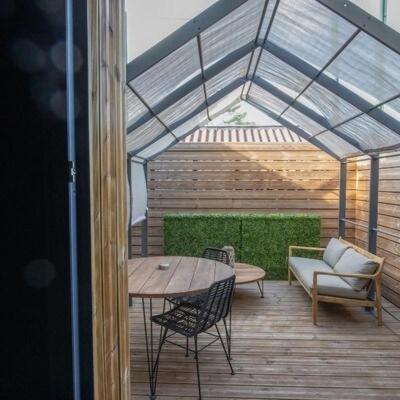 d'une terrasse avec une table et des chaises ainsi qu'un toit en verre. dans l'établissement Suite Chic - Antre-parenthèse, à Gravelines