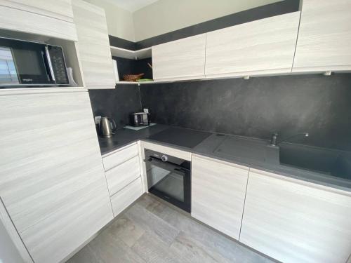 une cuisine avec des armoires blanches et un évier dans l'établissement Cannes proche Croisette - Studio moderne balcon, à Cannes