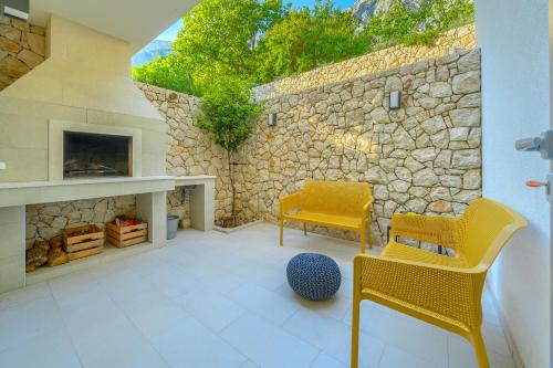 a living room with yellow chairs and a stone wall at Villa Bellevue Bast in Baška Voda