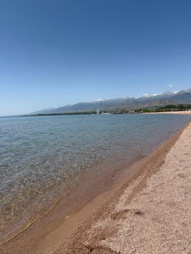 a beach with water and mountains in the background at Vzmorie apart #1 in Bosteri