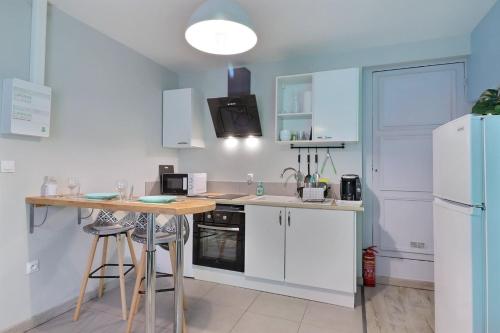 a kitchen with white cabinets and a table and a refrigerator at Les Apparts du Pont Vert - lit double - WiFi - tout inclus - 5 in Troyes
