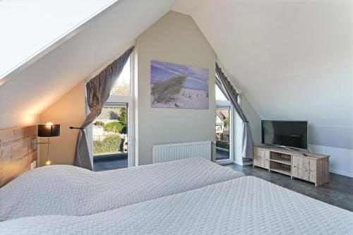 una camera da letto con un letto bianco e una televisione di Oude Nieuwelandseweg 33B - Ouddorp - Villa Hopper met jacuzzi, voor gebruik - NOT FOR COMPANIES a Ouddorp