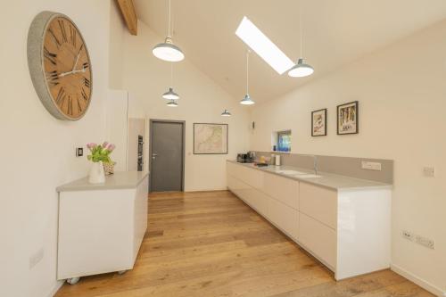 a kitchen with white cabinets and a large clock on the wall at The Neuk in Kincraig