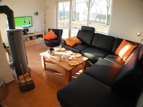a living room with a black couch and a table at Villa Seeblick - Nordhorn in Nordhorn