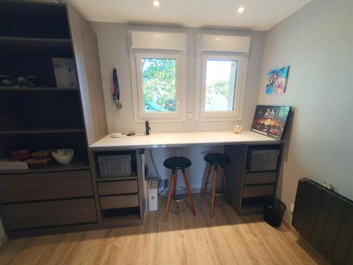 une cuisine avec un évier et deux tabourets sous une fenêtre dans l'établissement Appartement 50m2 indépendant dans maison familiale, à Arnage