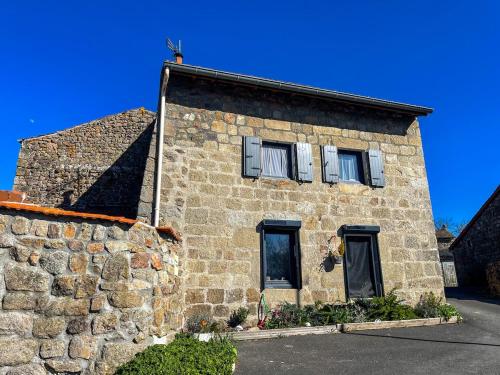 a stone building with two windows and a blue sky at L'Escapade Nordique - Bain Nordique - Sauna - WIFI - 3 étoiles in Grazac