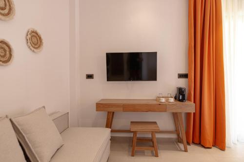 a living room with a table and a tv on a wall at Sarana Suites Crete in Kissamos