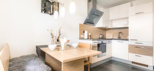 a kitchen with white cabinets and a wooden table at Höllhof Dachstein West in Russbach am Pass Gschütt