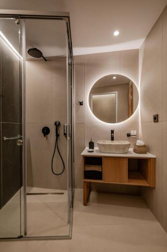 a bathroom with a sink and a shower with a mirror at Sarana Suites Crete in Kissamos