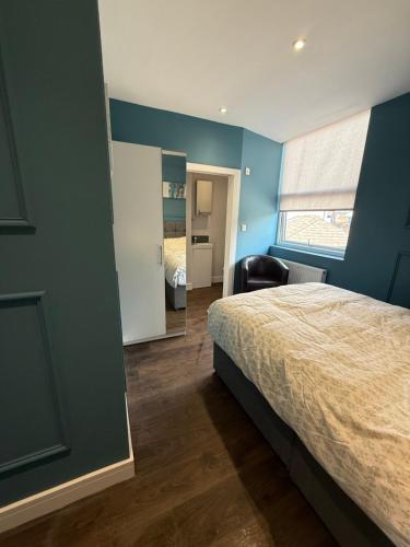 a bedroom with blue walls and a bed and a mirror at Turquoise Garden in Macclesfield