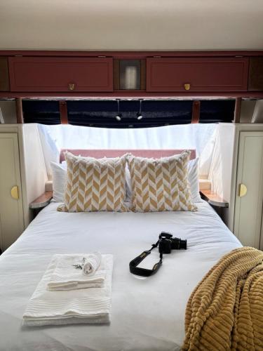 a bed with a camera and towels on it at Riverside Retreat in a Luxe Caravan in Sabie