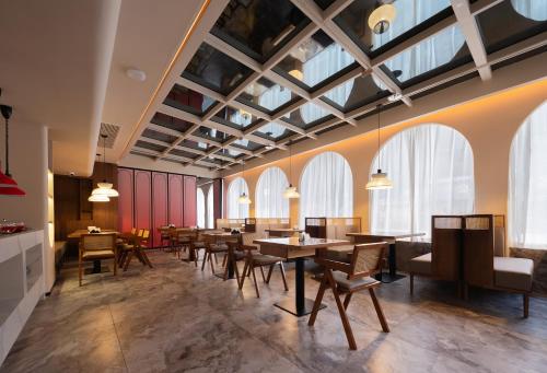 a restaurant with tables and chairs and windows at Zhangjiajie Yujie Hotel in Zhangjiajie