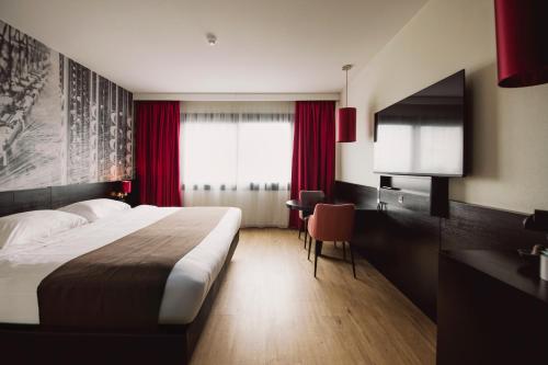 a hotel room with a large bed and a desk at Bastion Hotel Tilburg in Tilburg