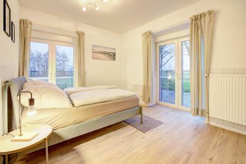 a bedroom with a bed and a table and windows at Beejenpütt in Westerdeichstrich