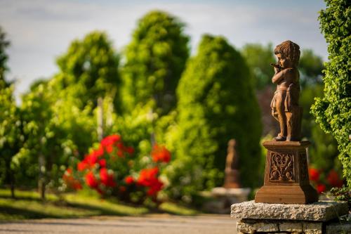 a statue of a boy standing on a stone pillar in a garden at Villa Luisa Francesca in Montebelluna