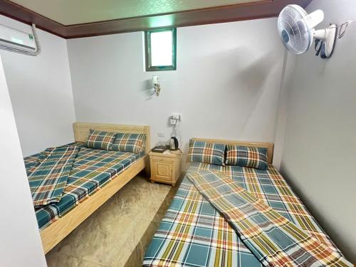 a bedroom with two beds and a fan at Homestay duy mạnh gần suối nước khoáng nóng trạm tấu in Cham Ta Lao