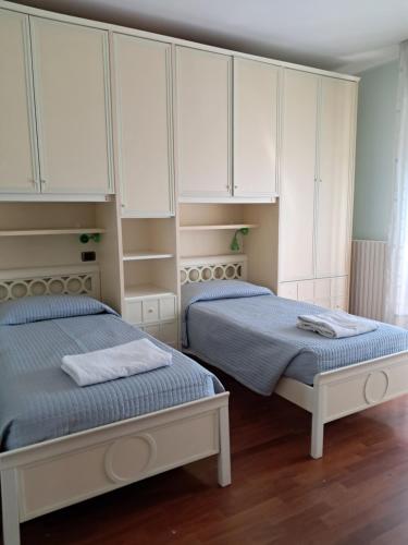 2 camas en un dormitorio con armarios blancos en Roses house, en Porto San Giorgio