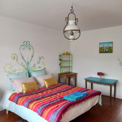 a bedroom with a bed with a colorful blanket at Chambres d'Hôtes Couleurs d'Elvine in Coutances