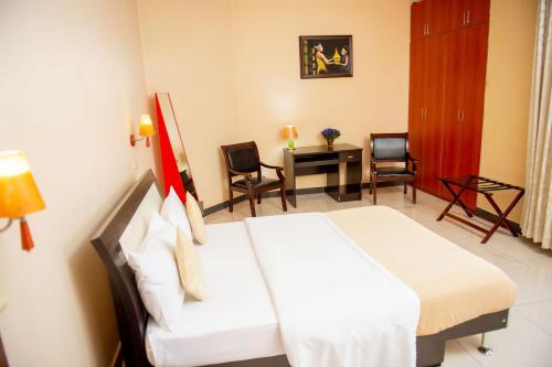 a hotel room with a bed and a table and chairs at Beausejour Hotel in Kigali