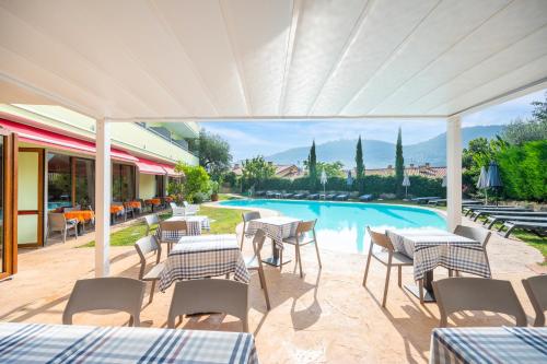 a patio with tables and chairs and a swimming pool at Hotel Alessandra in Garda