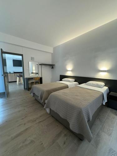 two beds in a hotel room with a tv at Sunflower Hotel Apartments in Larnaka