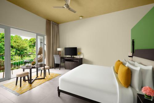 a bedroom with a white bed and a living room at Gateway Coorg in Madikeri