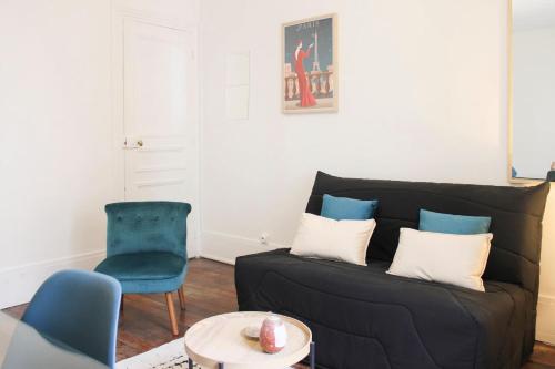 un salon avec un canapé noir et un fauteuil bleu dans l'établissement Comfort and calm at the gateway to Paris, à Saint-Denis