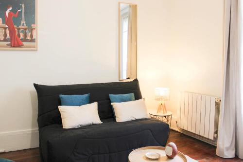 - un canapé noir avec des oreillers dans le salon dans l'établissement Comfort and calm at the gateway to Paris, à Saint-Denis