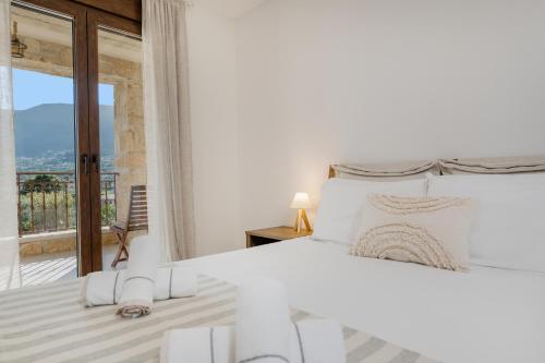a white bedroom with a bed and a balcony at Casa di Olivo in Alykes