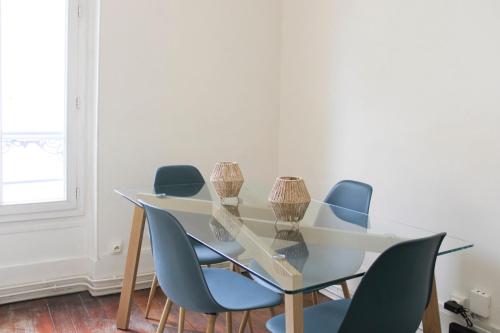 une table en verre avec des chaises bleues autour dans l'établissement Comfort and calm at the gateway to Paris, à Saint-Denis