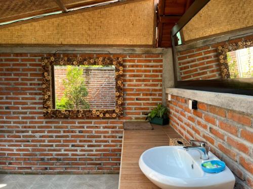 a bathroom with a brick wall and a sink at Villa Rumah Kayu Lovina in Lovina