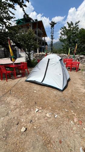 a tent sitting on the ground next to picnic tables at Wander Thrives iNN in Manāli
