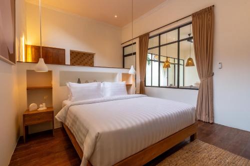 een slaapkamer met een wit bed en een raam bij Sofia Villa by betterplace in Canggu
