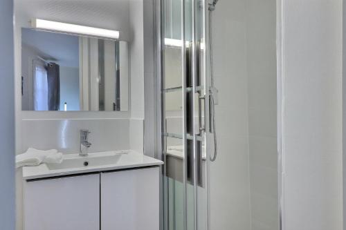 une salle de bain blanche avec un lavabo et une douche dans l'établissement Le Pithou - votre pied à terre équipé en ville 5, à Troyes