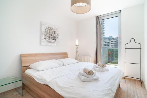 a white bedroom with a bed with towels on it at Bright 1BR Apt w Private Parking in Trnávka