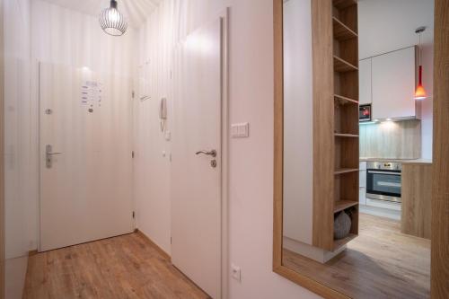 a white kitchen with a door and a mirror at Bright 1BR Apt w Private Parking in Trnávka