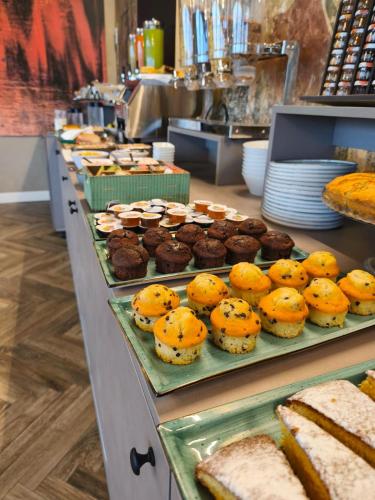 a buffet line with trays of muffins and bread at Hotel Vita in Salò