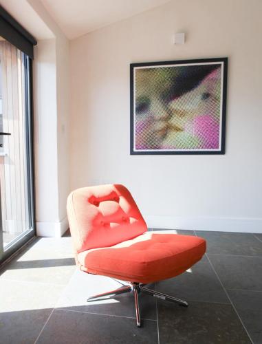 a red chair in a room with a picture on the wall at The Piggery near Bruton in Evercreech