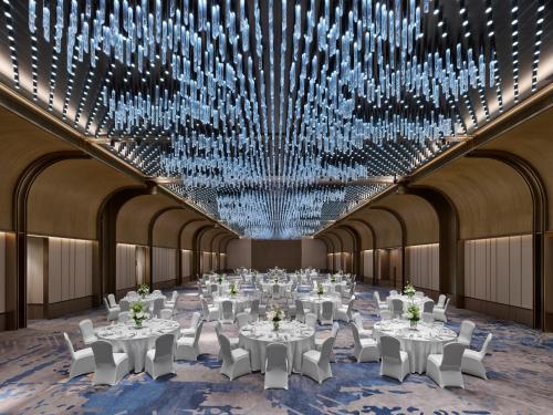 a ballroom with white tables and chairs and chandeliers at Hilton Shanghai Greater Hongqiao in Shanghai