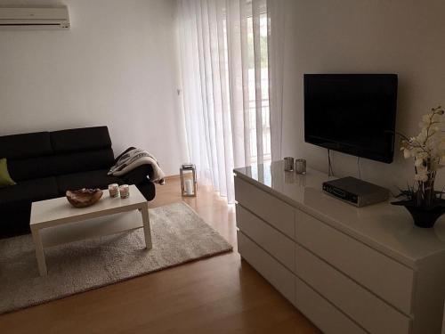 a living room with a flat screen tv on a dresser at App Marina NOVI in Novi Vinodolski
