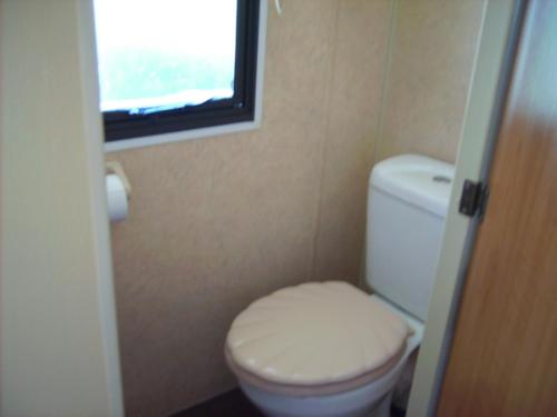 Elle comprend une petite salle de bains pourvue de toilettes et d'une fenêtre. dans l'établissement MOBIL HOME 3 à 5 PERSONNES, à La Celle-sous-Gouzon
