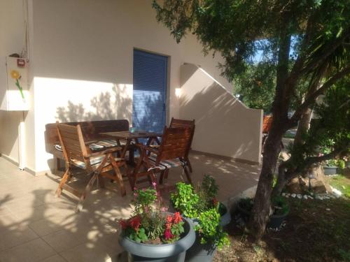 a patio with a table and chairs and a tree at Marieva Sea View Apartments in Kanali