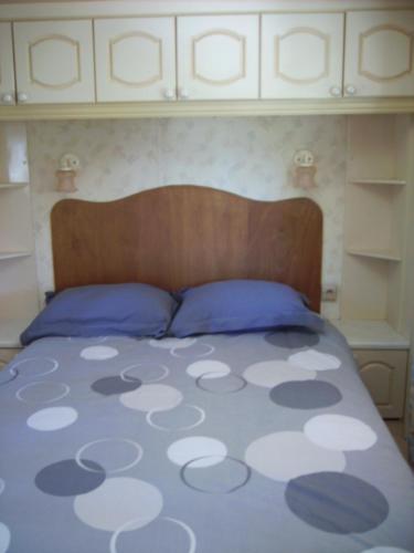 - un lit avec deux oreillers bleus et une tête de lit en bois dans l'établissement MOBIL HOME 3 à 5 PERSONNES, à La Celle-sous-Gouzon