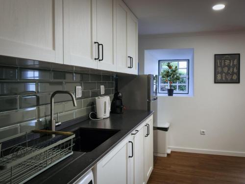 a kitchen with white cabinets and a sink at Casa da Leocádia in Rosais