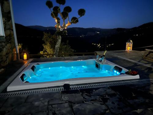 a jacuzzi tub on a patio at night at Casinha Serabigoes Arouca Passadiços Paiva in Arouca