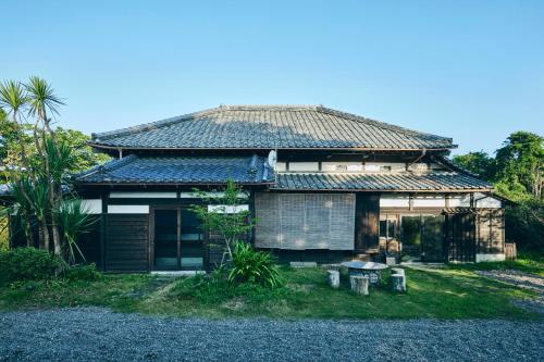 an old house with a tile roof on a yard at MUJI BASE kamogawa in Kamogawa